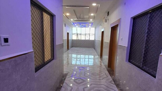 A hallway with a marble floor, blue LED lighting, and large windows at the end. - The Nirmala palace (Faizabad)