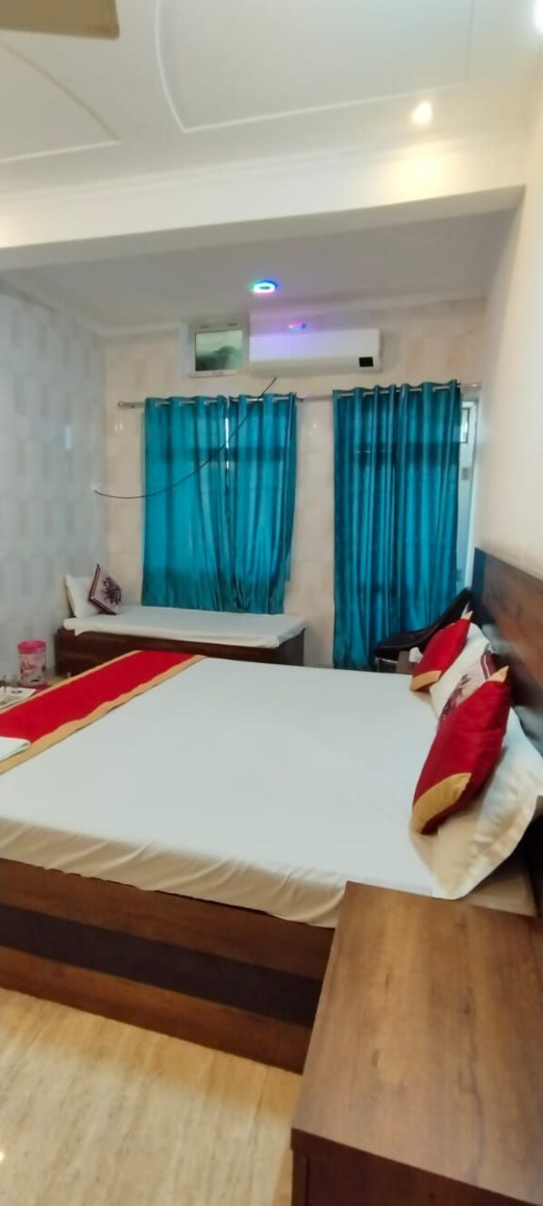 A hotel room with a large bed, a wooden headboard, a red runner, and blue curtains. - The Nirmala palace (Faizabad)