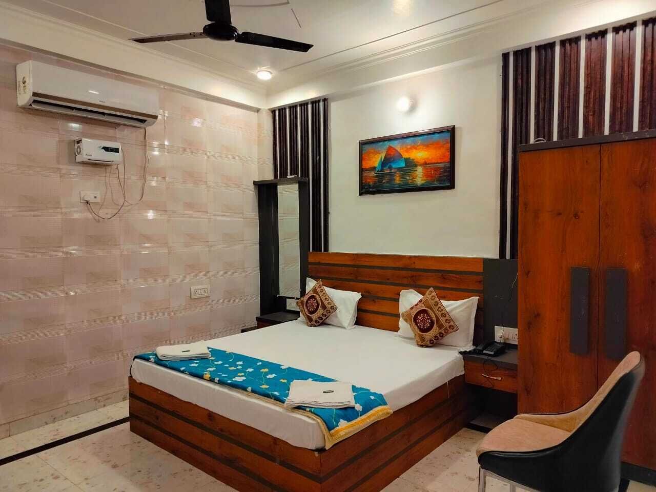 Un dormitorio ordenado con cama, mesita de noche, silla, armario y aire acondicionado.