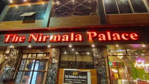 The Nirmala Palace hotel with a prominent sign, a reception area, and a view of the street. - The Nirmala palace (Faizabad)
