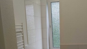 A small, modern bathroom with white tiles, a toilet, and a shower area. - Monteurzimmer mit Fast Wlan, Einzelbetten, Smart TV je Zimmer, Osnabrück (Osnabrück)