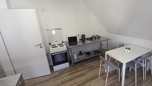 A compact kitchen with a stove, microwave, and small dining table with chairs. - Monteurzimmer mit Fast Wlan, Einzelbetten, Smart TV je Zimmer, Osnabrück (Osnabrück)