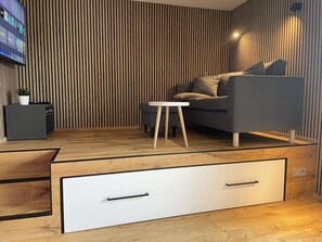 A modern living room with a sofa, a small table, a TV, and a cabinet. - Designer-fewo in der Nähe zum Südstrand (Borkum)