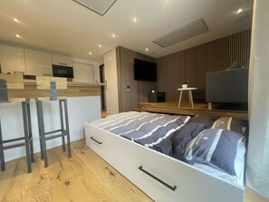 A modern bedroom with a bed, a small desk, and a TV. - Designer-fewo in der Nähe zum Südstrand (Borkum)