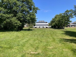 A modern building with a flat roof, surrounded by a grassy field and trees. - Designer-fewo in der Nähe zum Südstrand (Borkum)