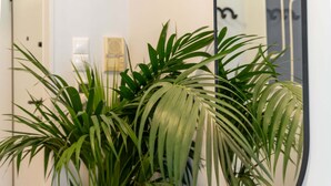 A hallway with a wooden console table, a potted plant, a mirror, and a lamp.