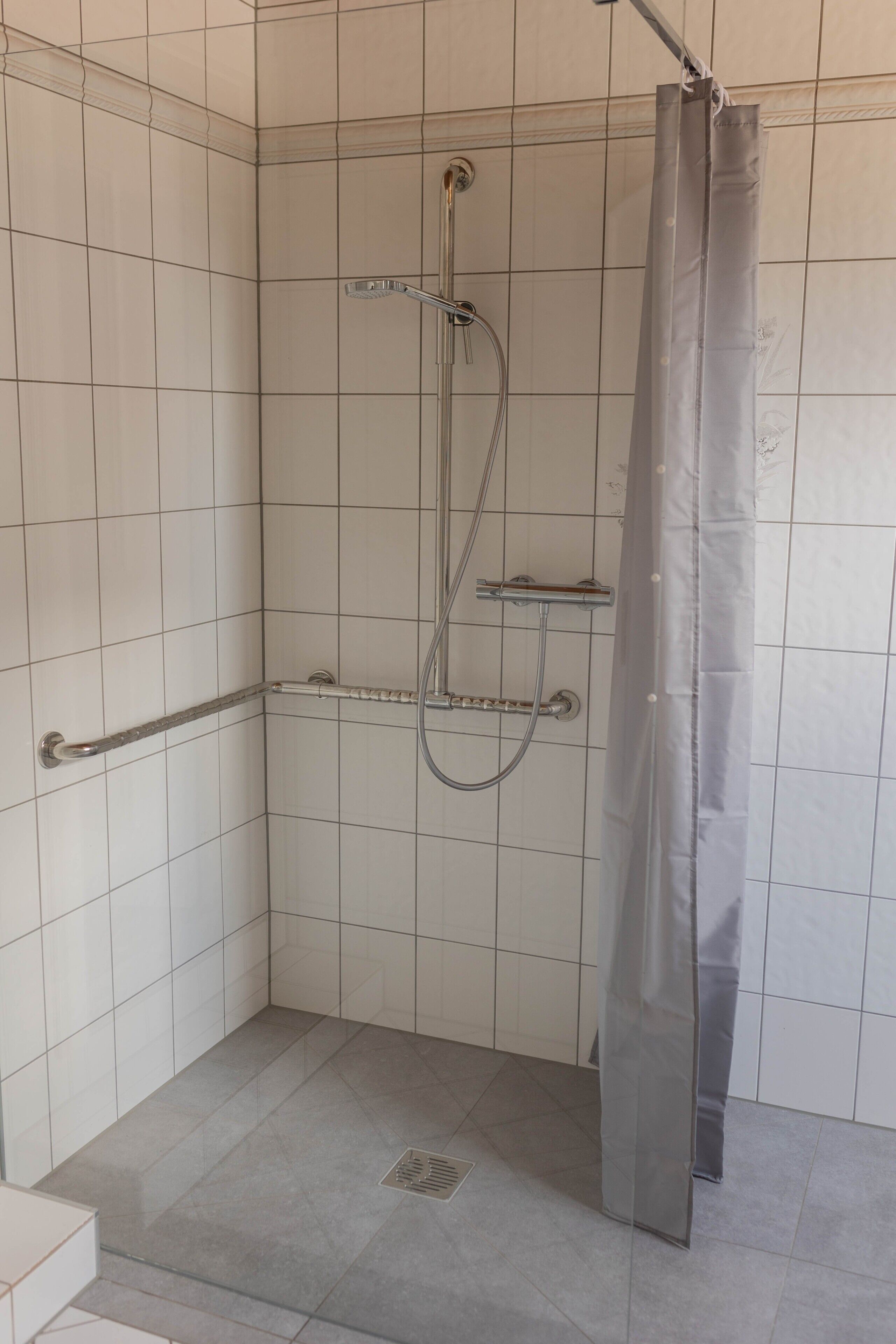 Una ducha con cabezal de ducha de mano, otro cabezal de ducha de mano y una cortina de ducha.
