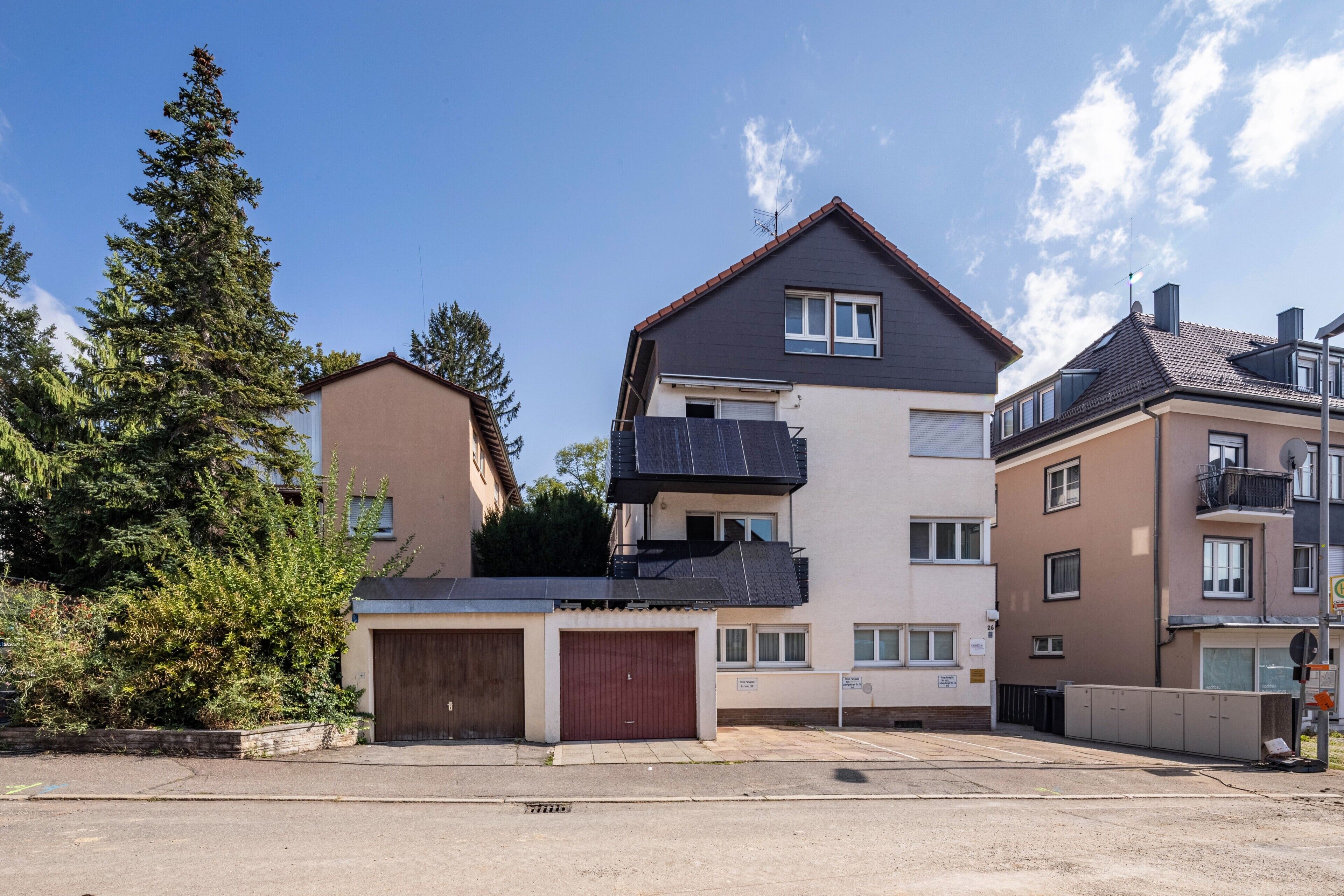 Ein mehrstöckiges Wohnhaus mit Garage, Balkon und Satellitenschüssel.