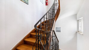 A wooden staircase with ornate black metal railings, a fire extinguisher on the wall, and a window on the right side. - Apartment 'Wohnung 03' with Balcony and Wi-Fi (Waiblingen)