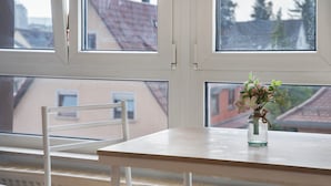 A room with a window, a table, a chair, and a vase with flowers. - Apartment 'Wohnung 06' with Wi-Fi (Waiblingen)