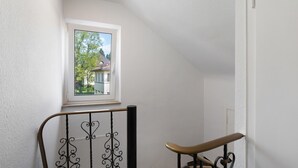 A staircase with a metal railing, a window with a view of a house, and a white wall. - Apartment 'Wohnung 06' with Wi-Fi (Waiblingen)