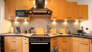 A modern kitchen with wooden cabinets, a built-in microwave, a stove, and a sink. - Apartment 'Neue 4 Zi Küche Bad Parknähe' with Balcony and Wi-Fi (Neunkirchen)
