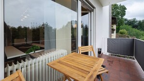 A balcony with a table and chairs, a radiator, and a view of greenery. - Apartment 'Neue 4 Zi Küche Bad Parknähe' with Balcony and Wi-Fi (Neunkirchen)