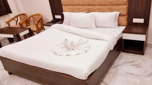 Una habitación de hotel con una cama grande, una mesita de noche de madera, una silla y una pequeña mesa.