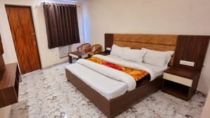 Un dormitorio con cama, mesitas de noche, televisor, armario y ventana con cortinas.