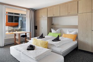 Una camera d'albergo con due letti, una scrivania e vista all'esterno.