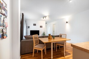 Un salon moderne avec une table à manger en bois, un canapé et un téléviseur.