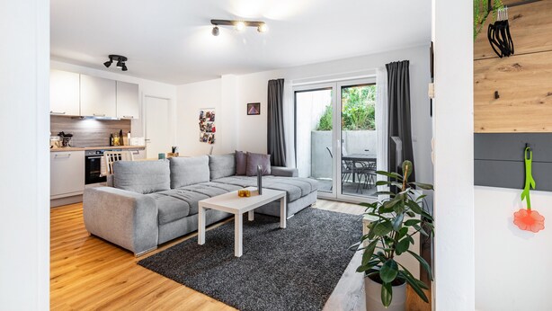 Una sala de estar moderna con un sofá gris, una mesa de centro blanca y un ventanal grande.