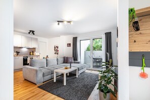 Ein modernes Wohnzimmer mit grauem Sofa, einem weißen Couchtisch und einem großen Fenster.