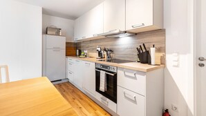 Una cocina moderna con armarios blancos, encimera de madera, horno empotrado y cafetera.