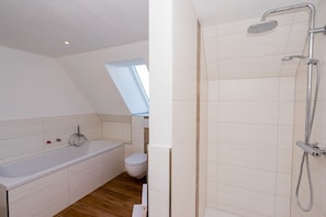 A modern bathroom with a bathtub, toilet, and shower. - Apartment '2_fewo Mittschiffs' with Shared Garden and Wi-Fi (Pellworm)