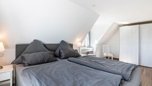 Ein modernes Schlafzimmer mit einem großen Bett, einem Nachttisch, einer Lampe und einem Sessel.