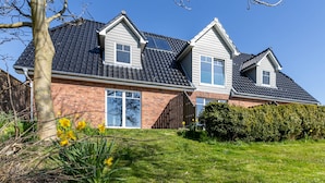 Ein zweistöckiges Haus mit Backsteinfassade, einem Ziegeldach und einem gepflegten Rasen.