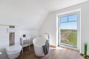 Un bagno moderno con una vasca freestanding, un water e un piccolo mobile lavabo.