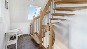 Um interior moderno com uma escada de madeira, uma mesa branca e uma janela com vista.