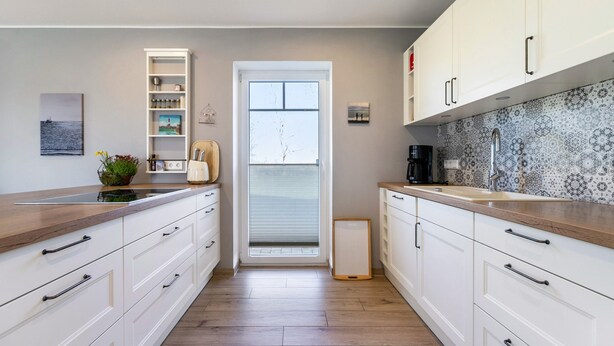 Una cocina moderna con armarios blancos, encimera de madera y un salpicadero con diseño.