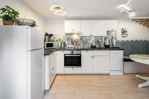Una cocina moderna con armarios blancos, horno empotrado, microondas y lavavajillas.