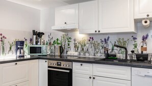 Una cocina moderna con armarios blancos, microondas, horno y pileta.