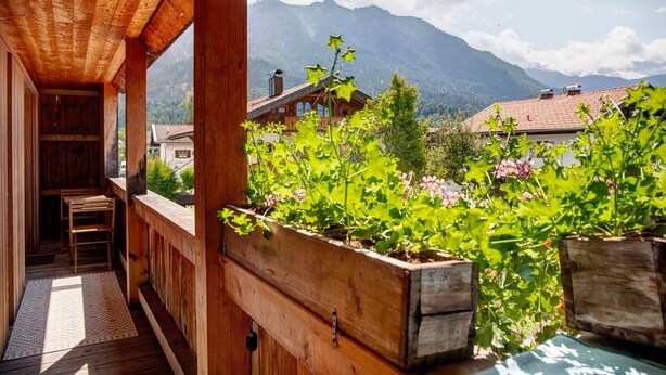A wooden balcony with a view of mountains and a village. - Room 'Apartment Mit Bergblick' with Mountain View, Balcony and Wi-Fi (Krün)