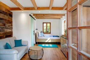 Une pièce avec un lit en mezzanine, un canapé, une table ronde et des poutres en bois au plafond.