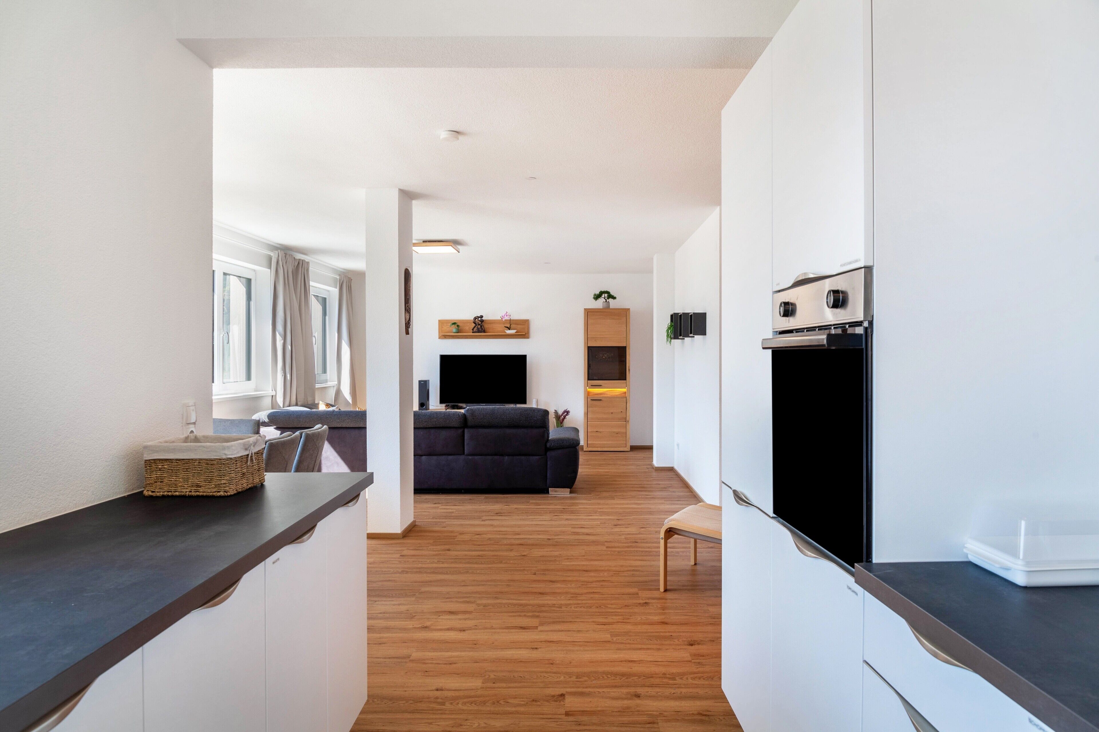 A modern kitchen with white cabinets, a wooden countertop, and a built-in oven.