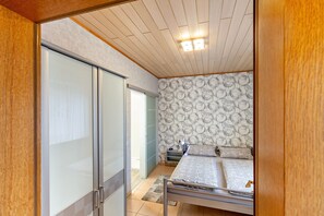 Une chambre à coucher comprenant un lit, une table de chevet, une commode, une armoire et un mur décoré d’un motif.