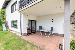 Une maison moderne dotée d’un patio, d’une porte coulissante et d’une petite table avec des chaises.