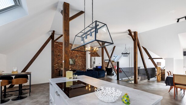 Une cuisine moderne dotée d’un îlot central, de murs en briques apparentes et d’un plafond de style industriel.
