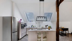 Une cuisine moderne dotée d’un îlot central, d’appareils électroménagers intégrés et de fenêtres de toit.