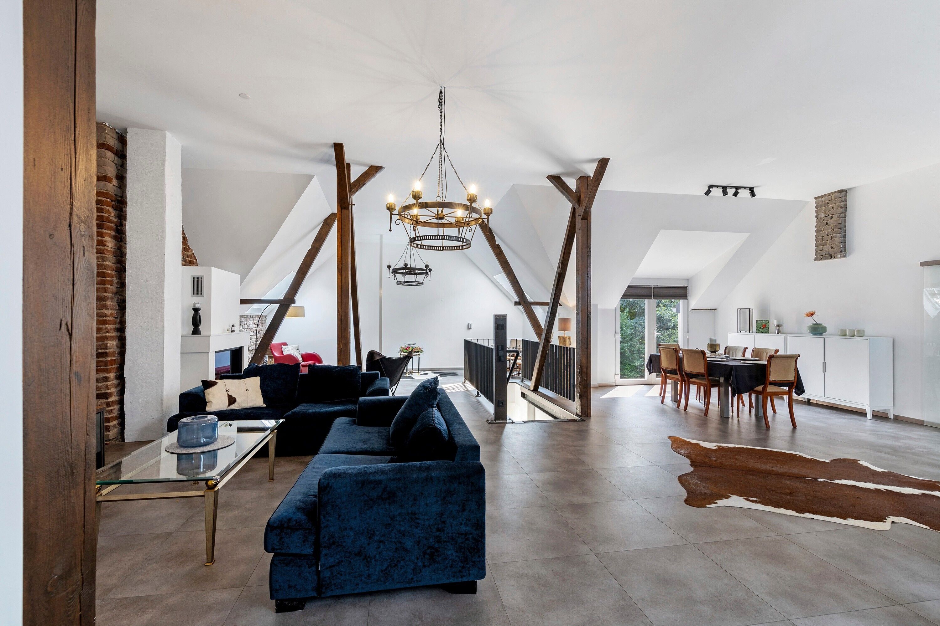 A spacious living area with a sofa, dining table, and a chandelier.