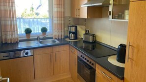 Una cucina compatta con mobili in legno, forno a incasso, macchina del caffè e tostapane.