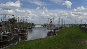 Una marina con imbarcazioni ormeggiate lungo l'acqua, un terrapieno erboso e un cielo nuvoloso.