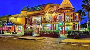 A brightly lit building with a distinctive conical roof and multiple levels, featuring a variety of shops and restaurants on the ground floor.