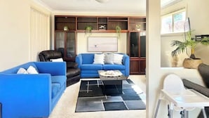 A living room with a blue sofa, a black leather chair, a coffee table, and a bookshelf.