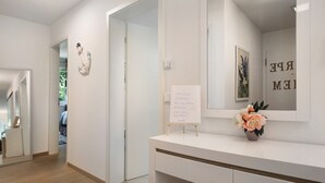 A modern bathroom with a white vanity, a mirror, and a small potted plant.
