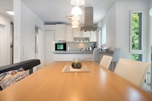Eine moderne Küche mit weißen Schränken, einem Holztisch und einer Pendelleuchte.