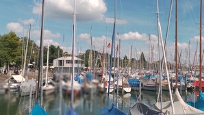 A marina with numerous boats docked, a building with a flat roof, and a clear sky.