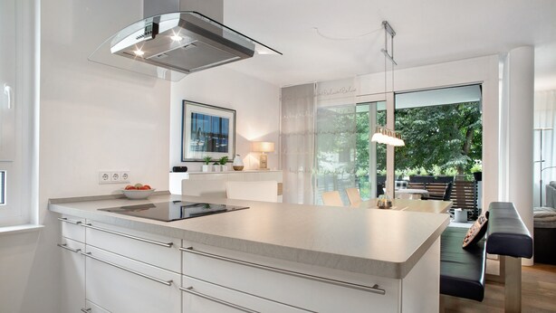 A modern kitchen with a large island, stainless steel appliances, and a view of the outdoors.
