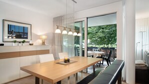 A modern dining area with a wooden table, bench, and pendant lighting.