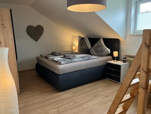 A modern bedroom with a loft bed, a heart-shaped wall decoration, and a wooden floor.